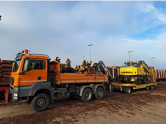 LKW-Kipper und Tieflader mit Bagger auf Materialplatz